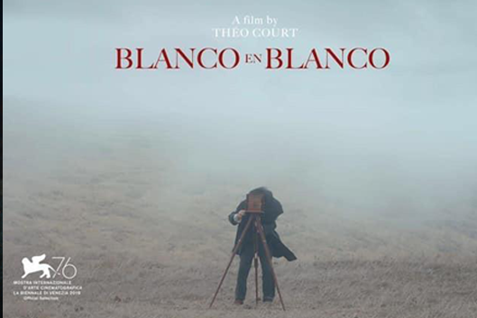 still from Blanco en Blanco; a man takes a photo with an old fashioned camera